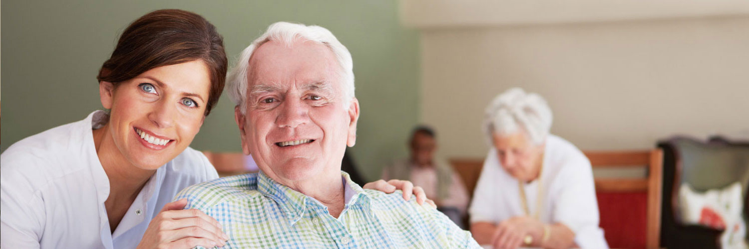 Caregiver and elderly man looking happily at the camera